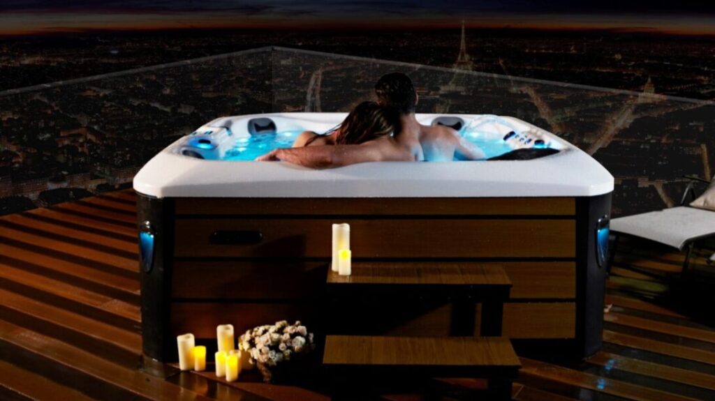 Masažni bazen na terasi s svečami in objetim parom v vodi.